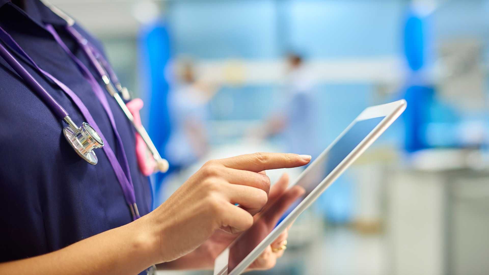 A doctor is using a tablet computer in a hospital room.
