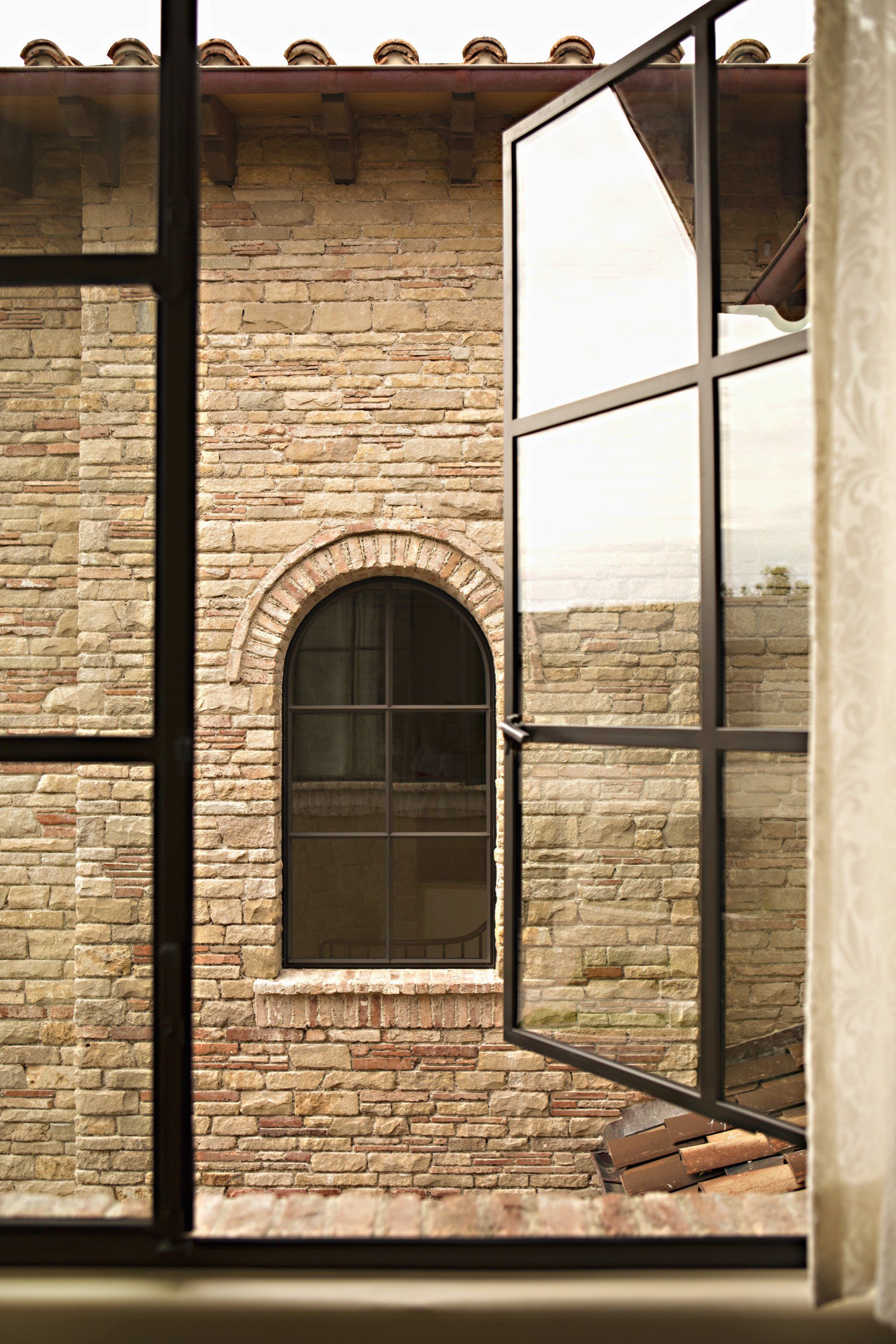 Window looking out in a Tuscan stone villa in Corona Del Mar designed by Oatman Architects