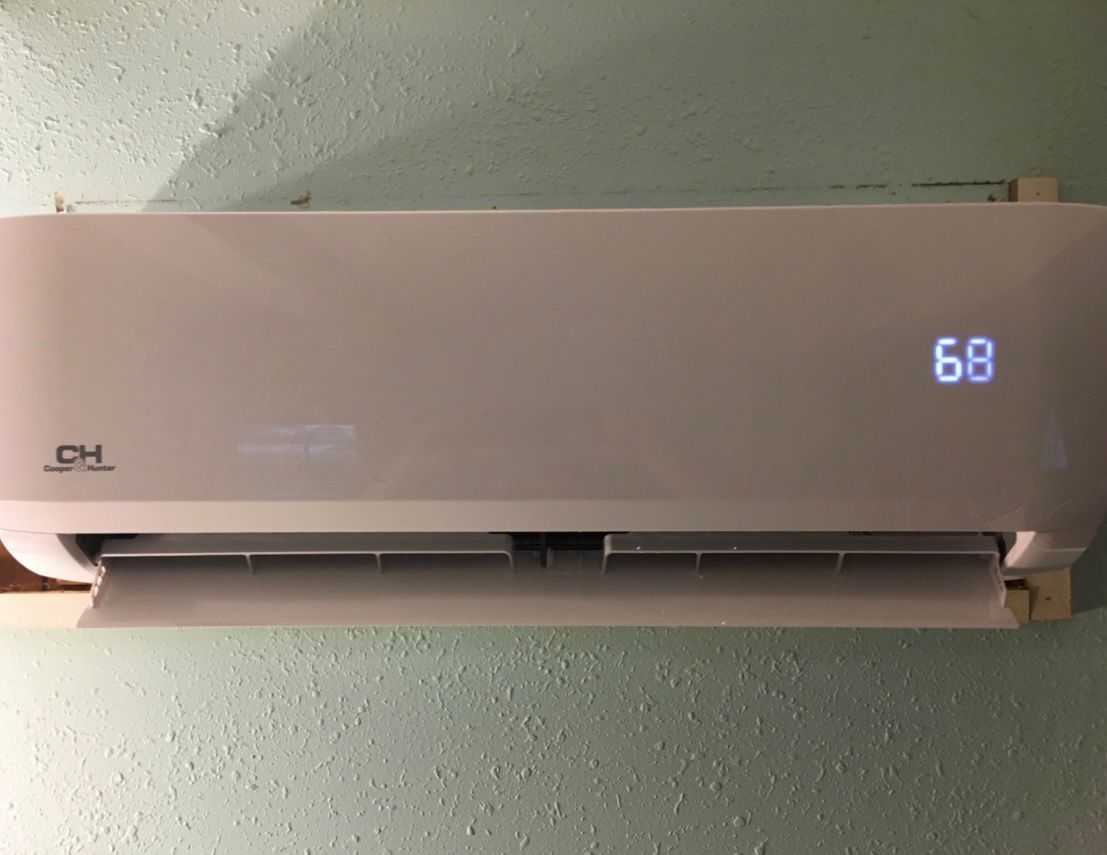 Wall-mounted air conditioner with digital display showing 68