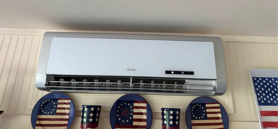 Wall-mounted air conditioner above patriotic U.S. flag-themed decorations on a pegboard wall