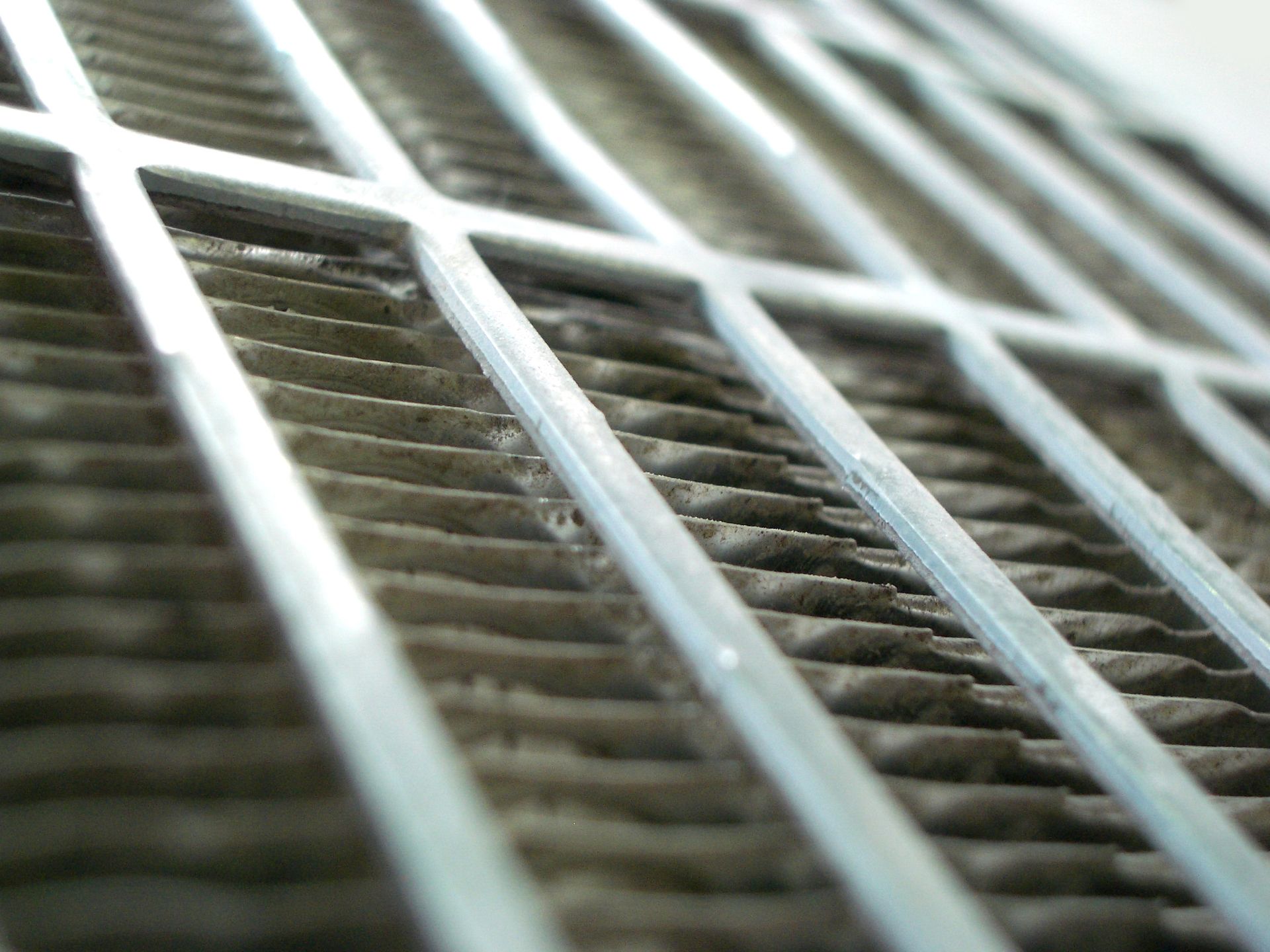 Close-up of a metal grate with diagonal white bars and dark slats behind it