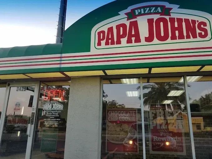Papa John's pizza storefront with green and red awning and glass windows.