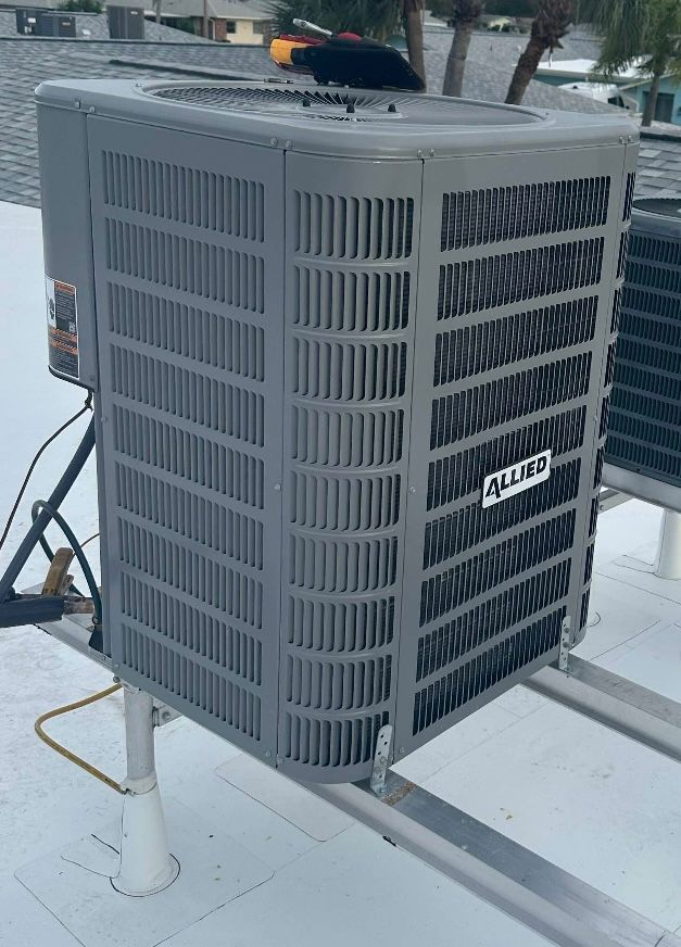Gray rooftop HVAC unit with vented panels on a white roof, with a yellow tool on top.