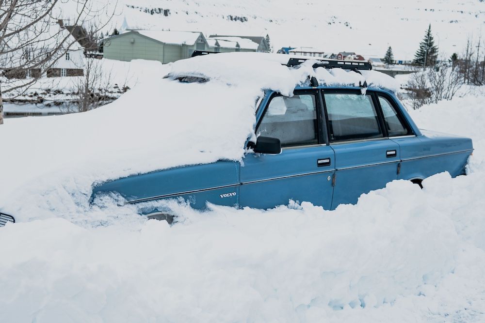 blue car buried in snow needs a winch out