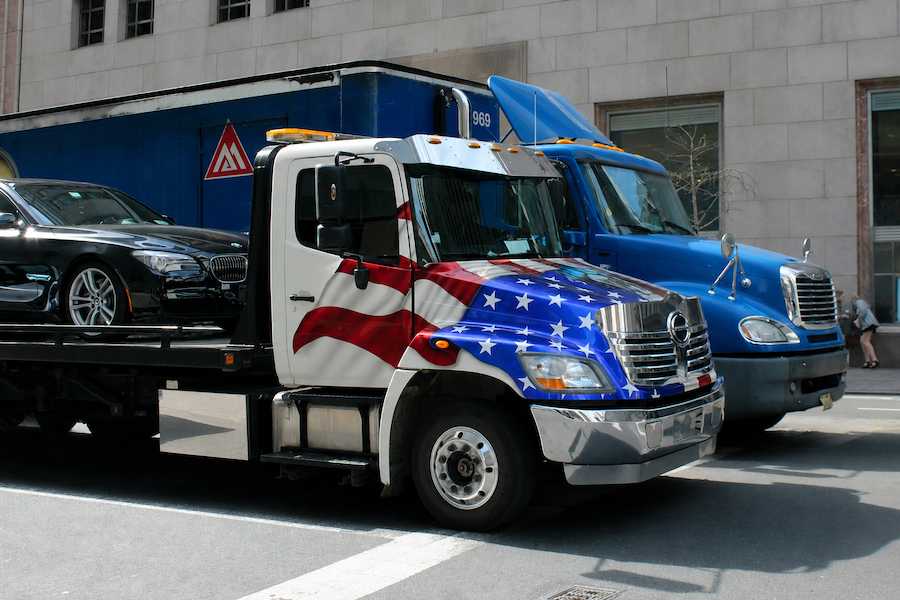 luxury car being transported through the city on flatbed tow truck