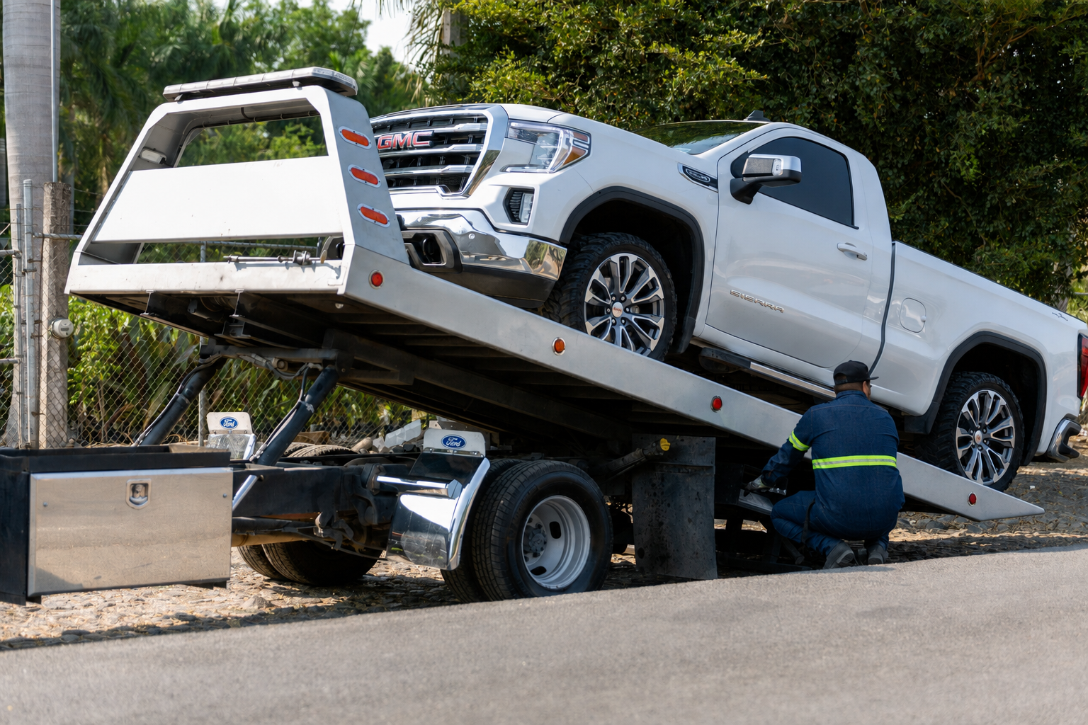 tow worker placing white pickup truck on flatbed