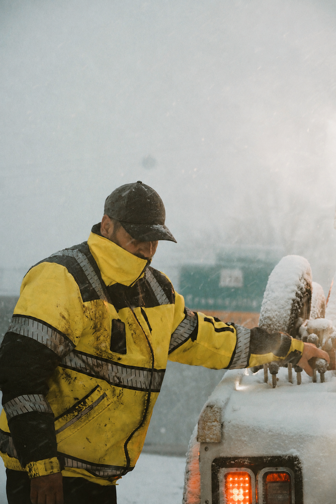 tow worker winching out a car in a snow storm