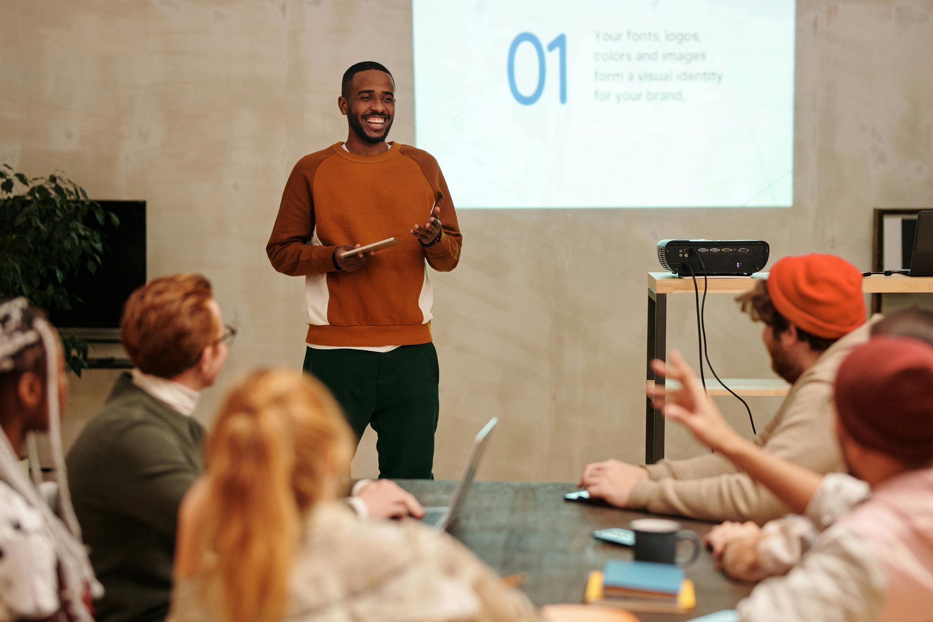 Man presenting to a group in a meeting, using a projector.