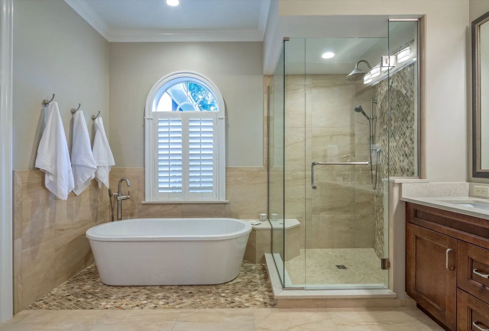Bright bathroom with freestanding tub, glass shower, and beige tile floor
