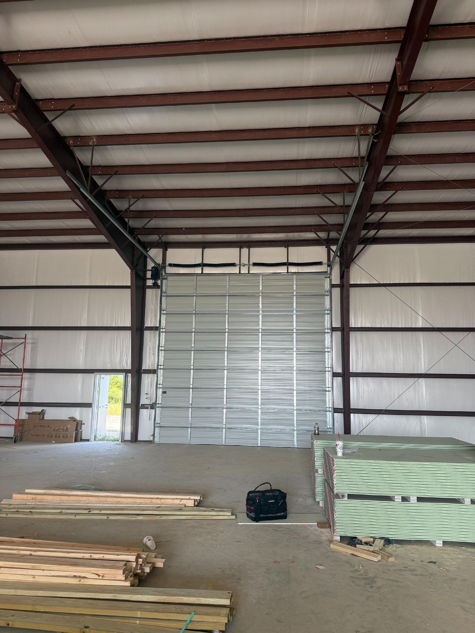 Interior of a building with a large metal door, insulation, and building materials.
