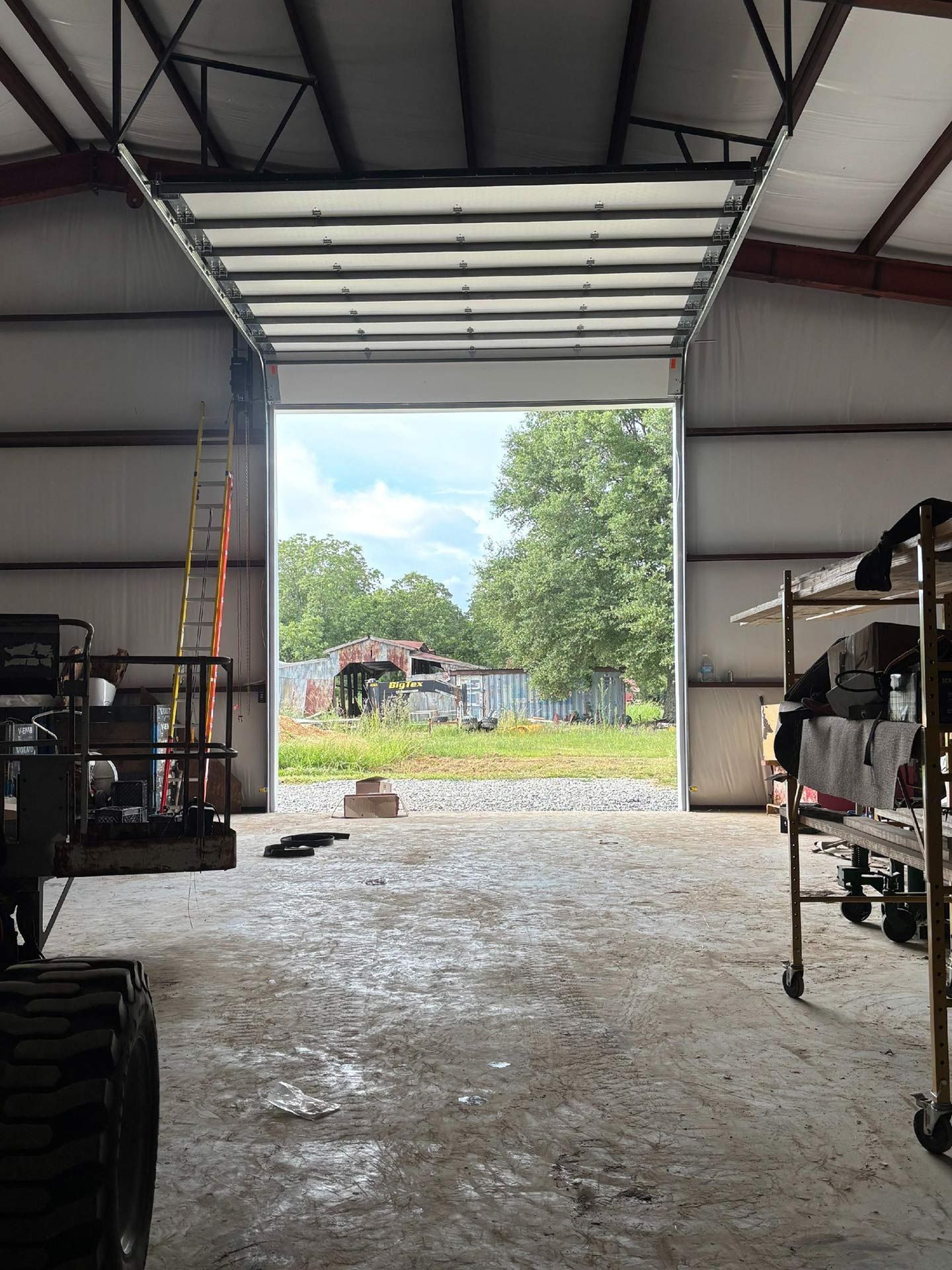 Open garage door framing a view of outdoor structures and trees.