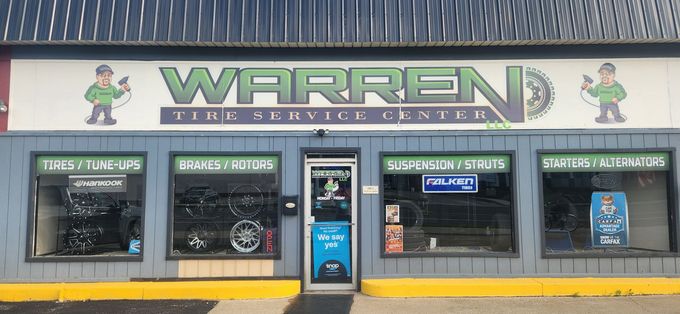 Storefront of Warren’s with green sign, large windows, and a central entrance on a sunny street.