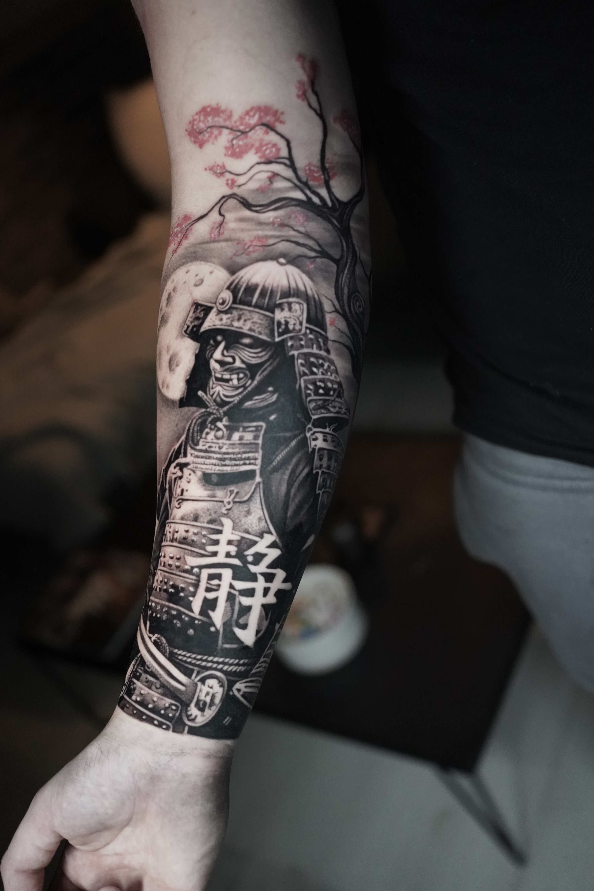 Black and white samurai arm tattoo with cherry blossoms and full moon. Chinese character 