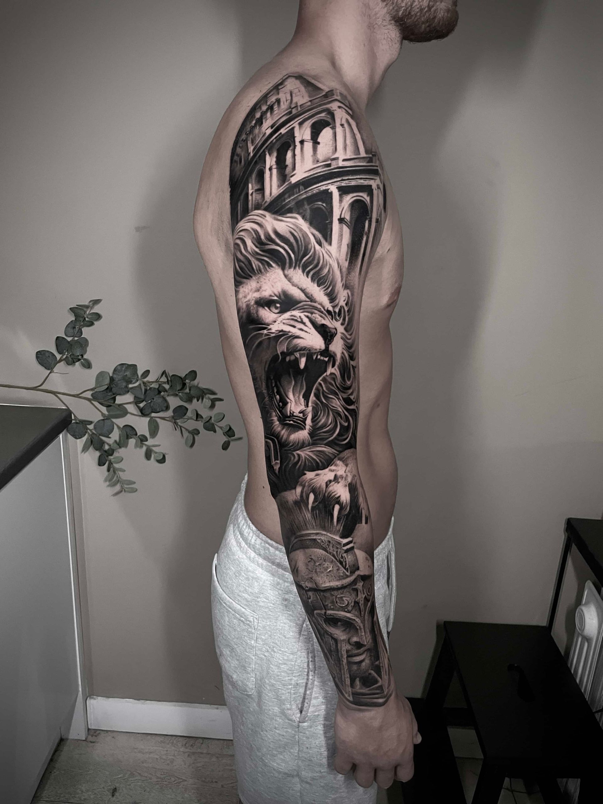 Man with full sleeve tattoo featuring a lion, Roman architecture, and other details.