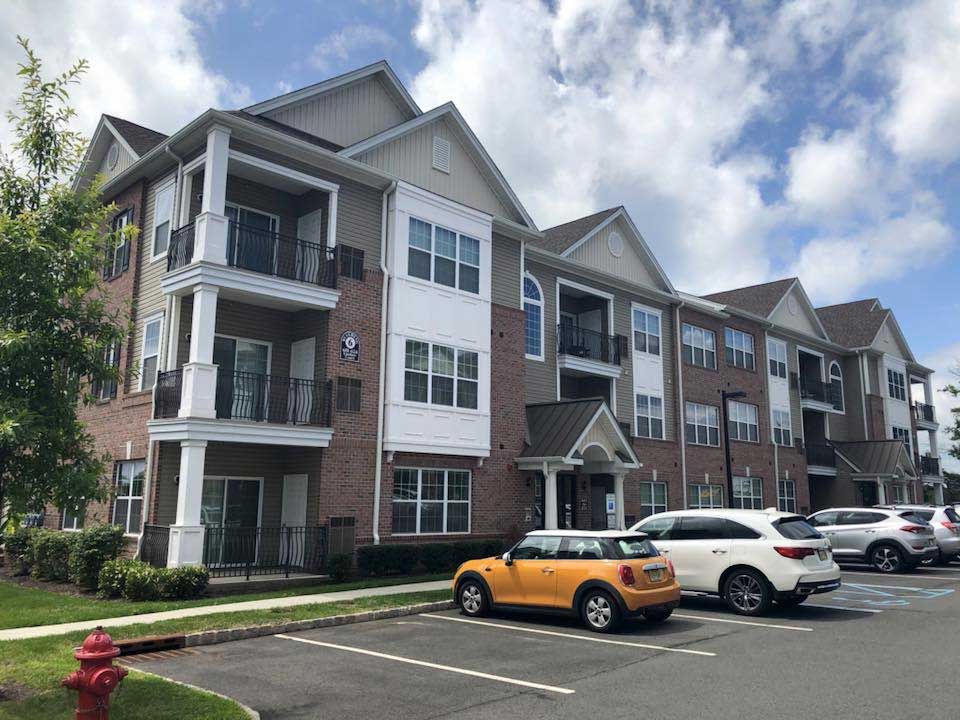 A large apartment building with cars parked in front of it.