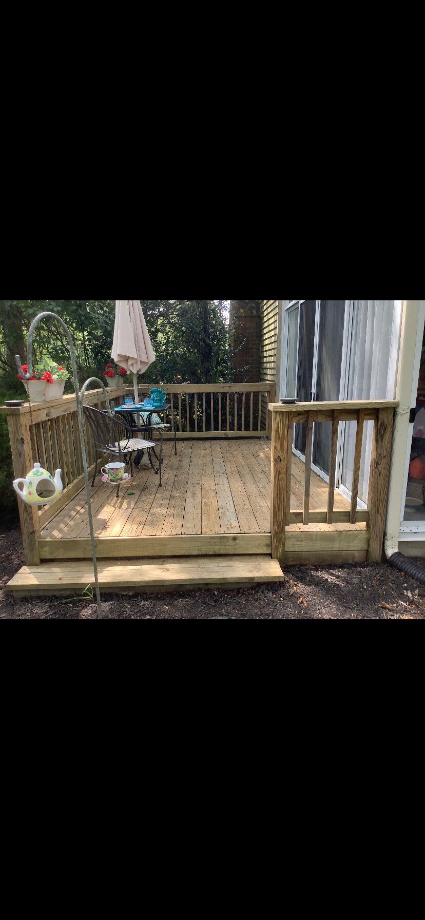 A wooden deck with stairs leading up to it and a sliding glass door.