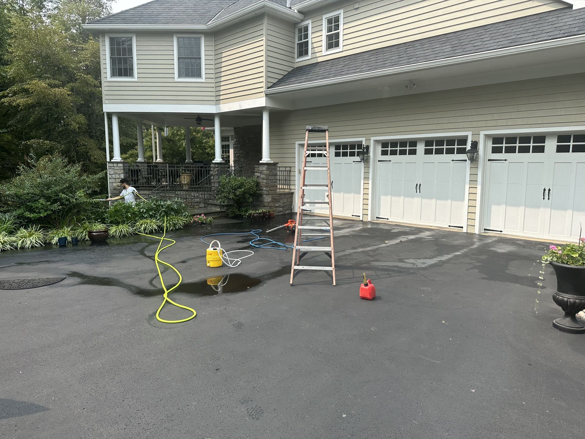 A ladder is sitting in a driveway in front of a house.