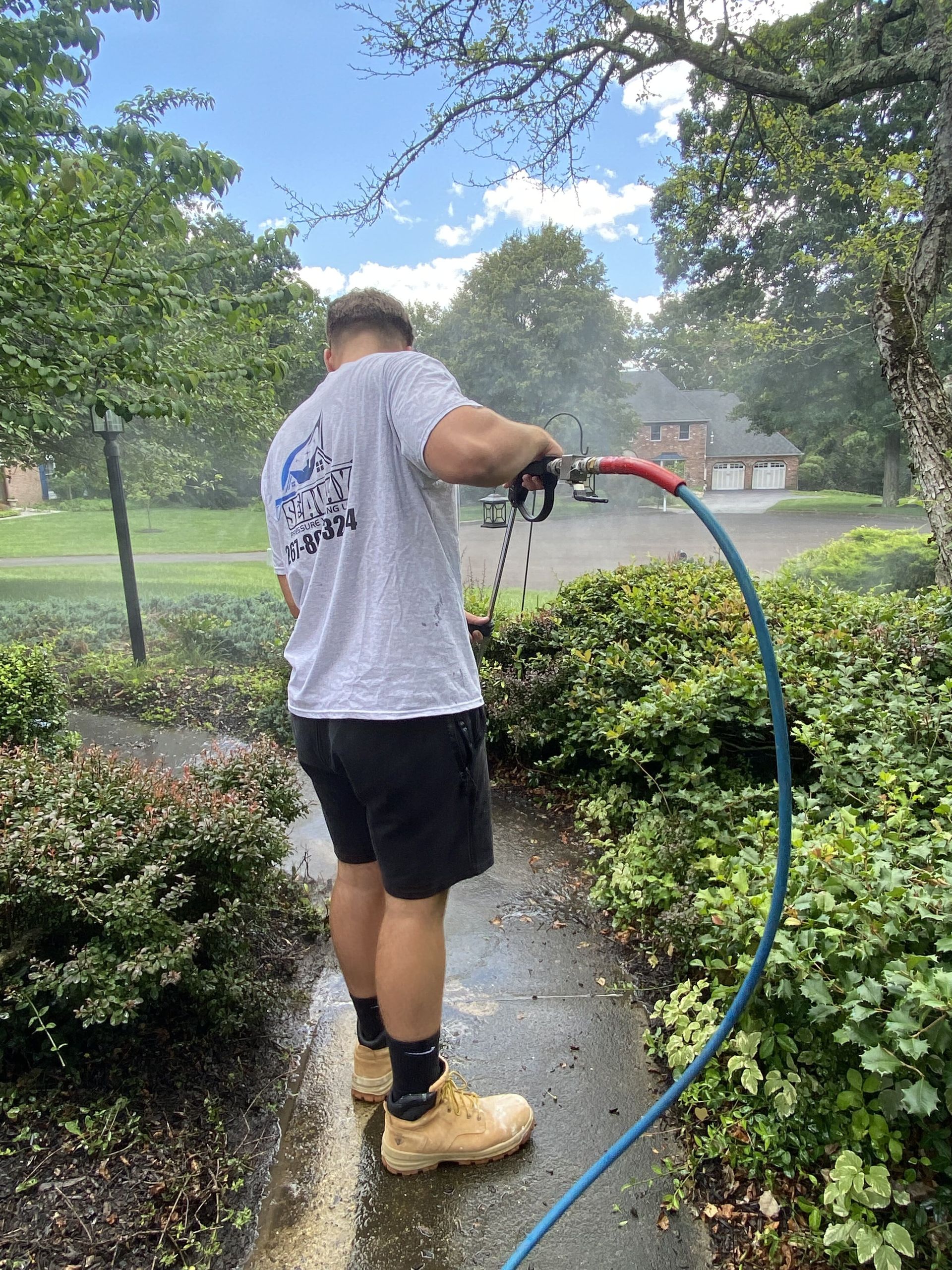 A man is cleaning a sidewalk with a hose.
