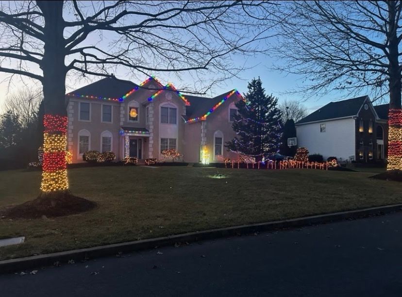 A large house is decorated with christmas lights and a christmas tree.