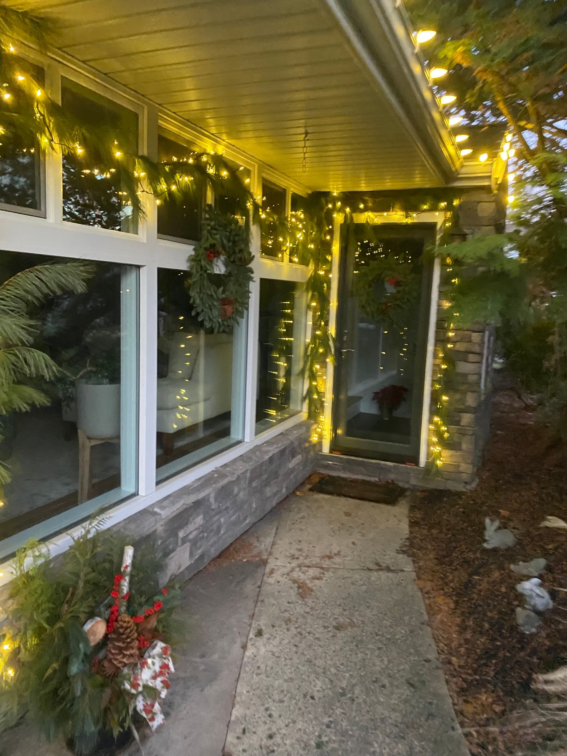The front of a house is decorated with christmas lights and a wreath.