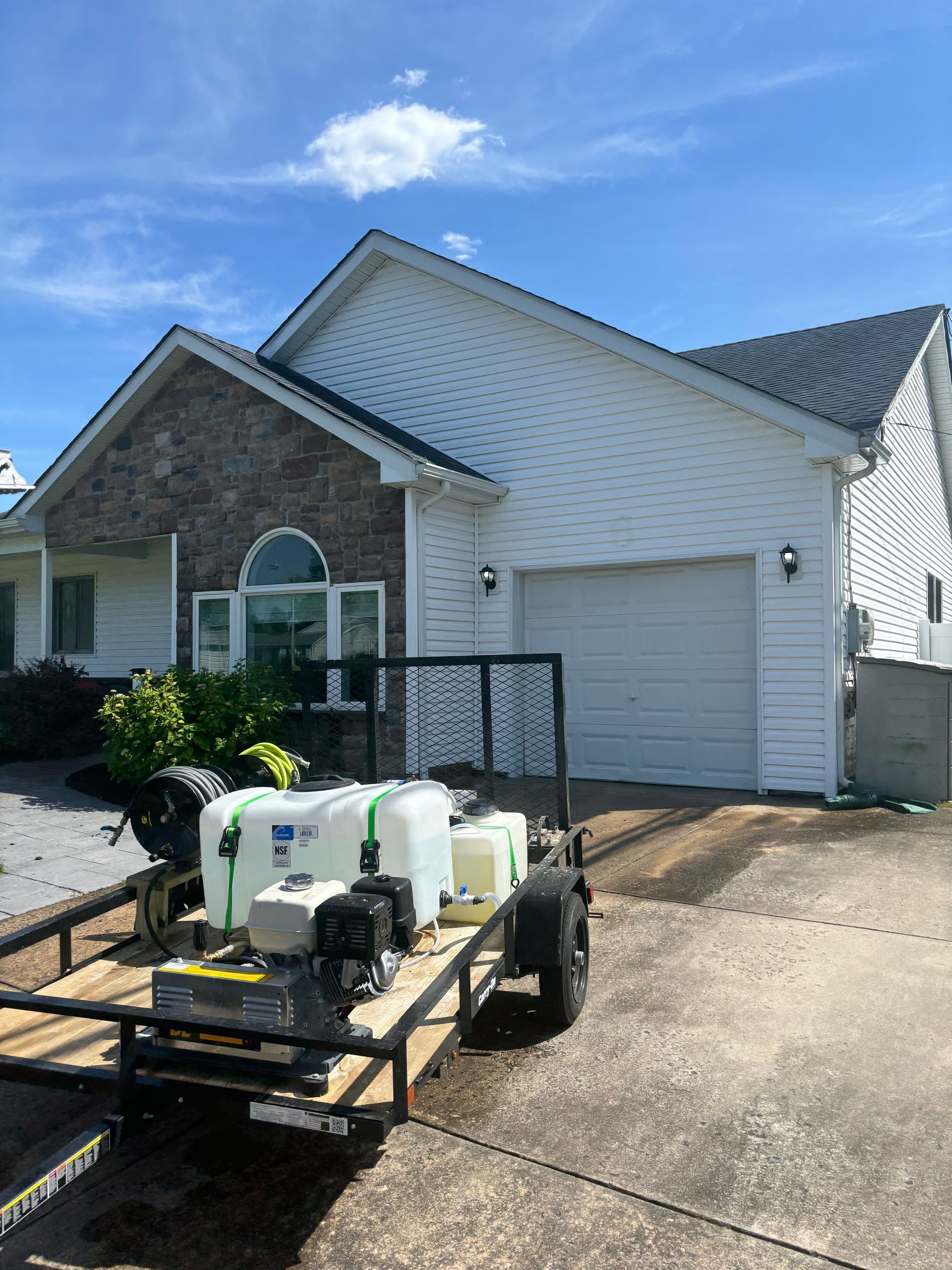 A pressure washing trailer parked in front of a house.