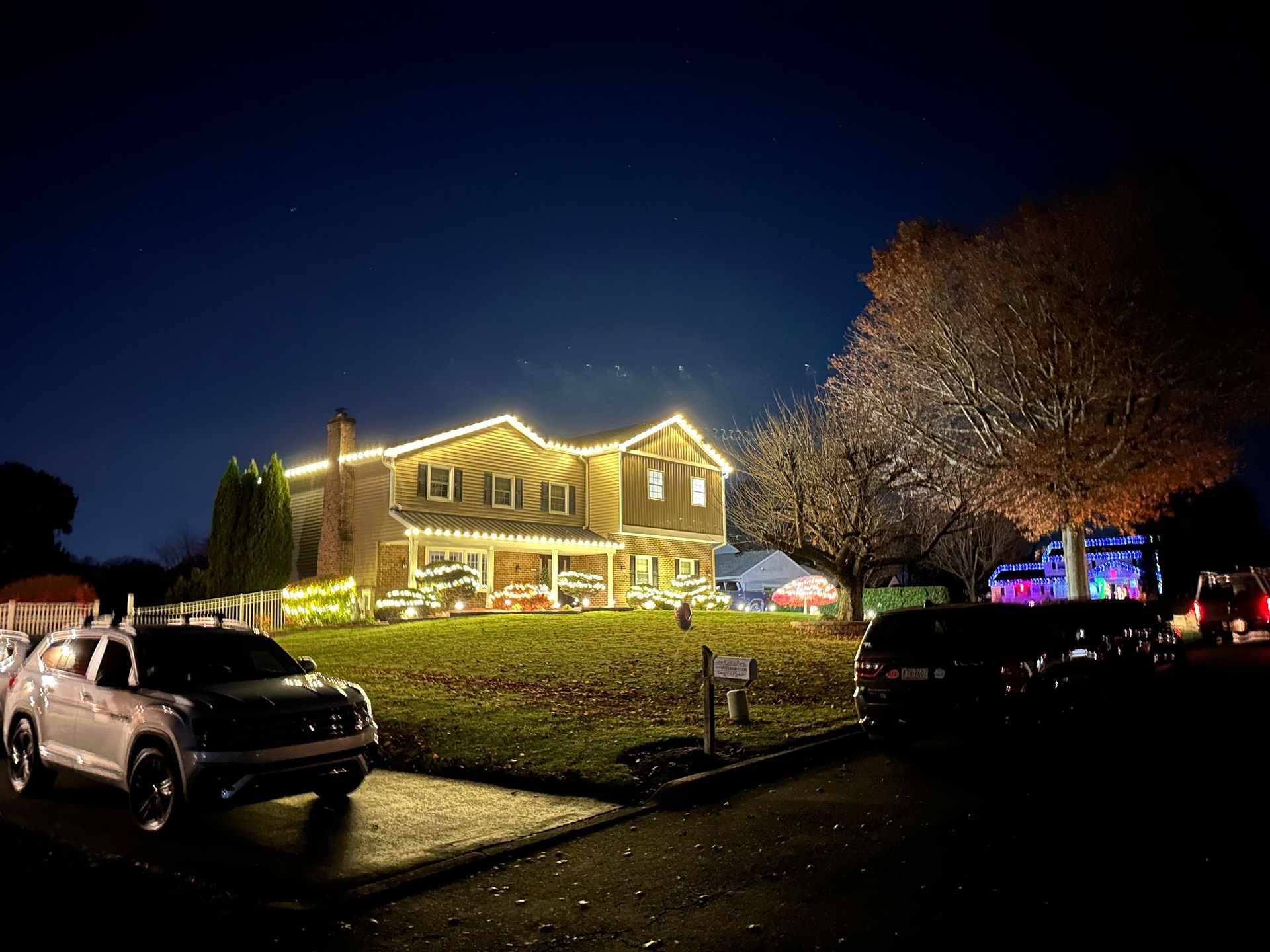 A house decorated with christmas lights is lit up at night.