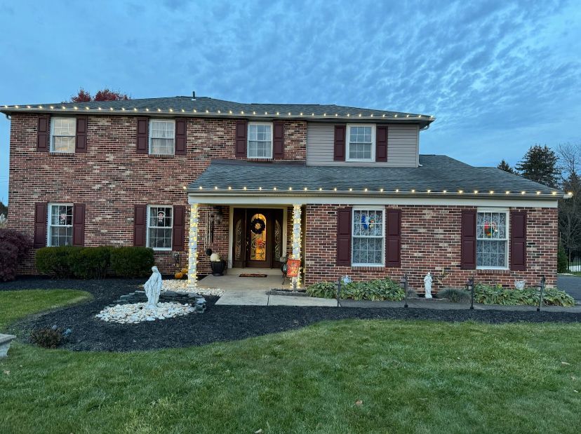 A large brick house with christmas lights on the roof