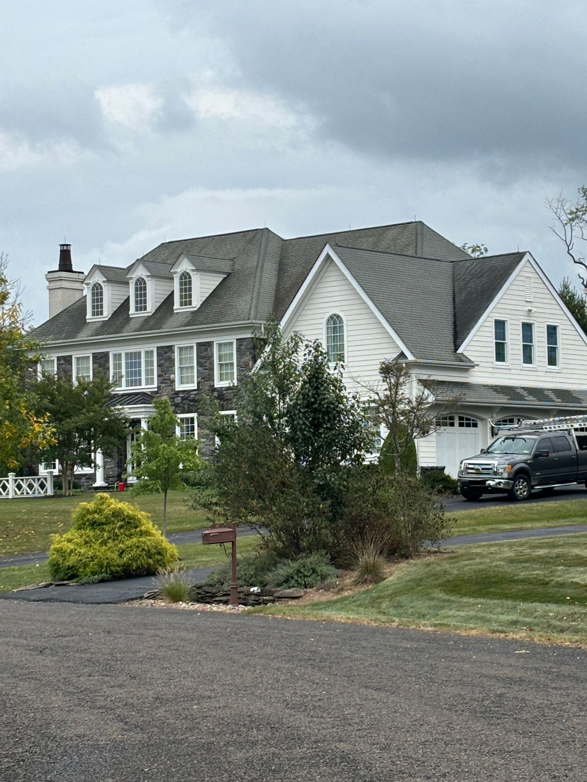 A large white house with a black truck parked in front of it.