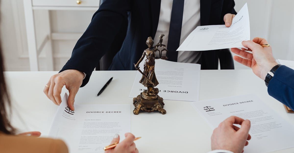 A group of people are sitting around a table with papers and a statue of justice.