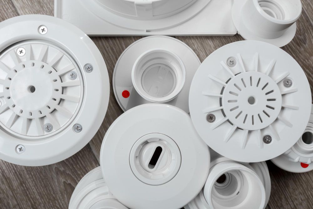 A pile of white swimming pool parts on a wooden floor.