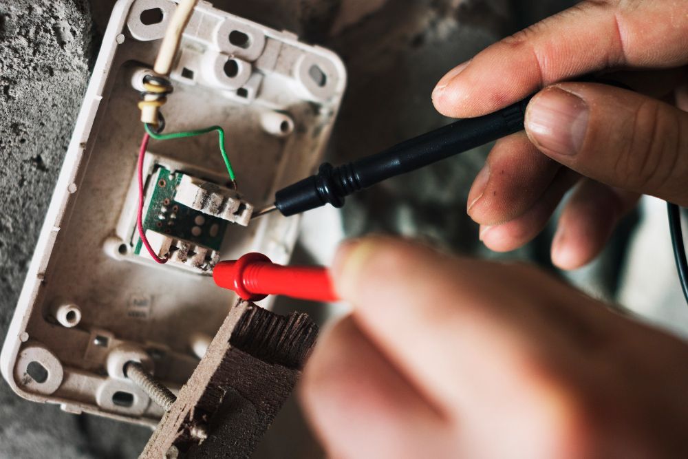 A person is using a multimeter to test an electrical outlet.