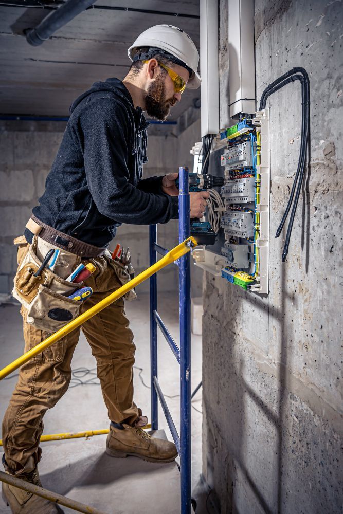 A man is working on an electrical box on a scaffolding.