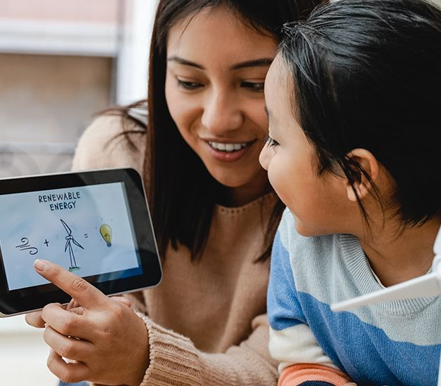 A woman and child are looking at a tablet that says renewable energy