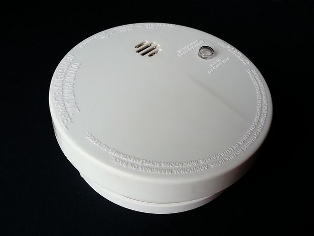 A white smoke detector on a black background