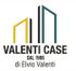 Logo di Valenti Case con sagome di edifici gialle e blu, testo “DAL 1986 di Elvio Valenti”