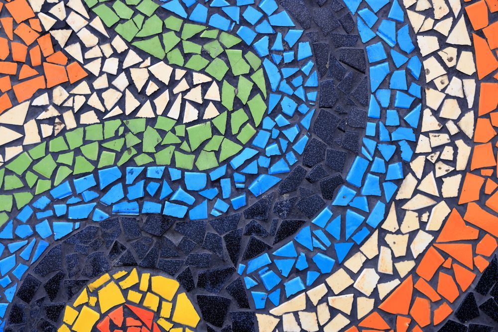 Mosaico colorato con motivi curvilinei a spirale nei toni del blu, verde, arancione e crema.