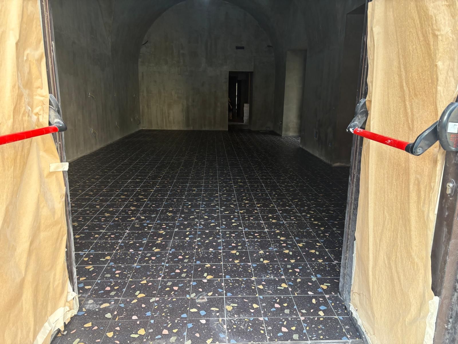 Ingresso del tunnel rivestito di moquette con pareti color beige e fasce rosse su entrambi i lati, che conduce a un interno buio.