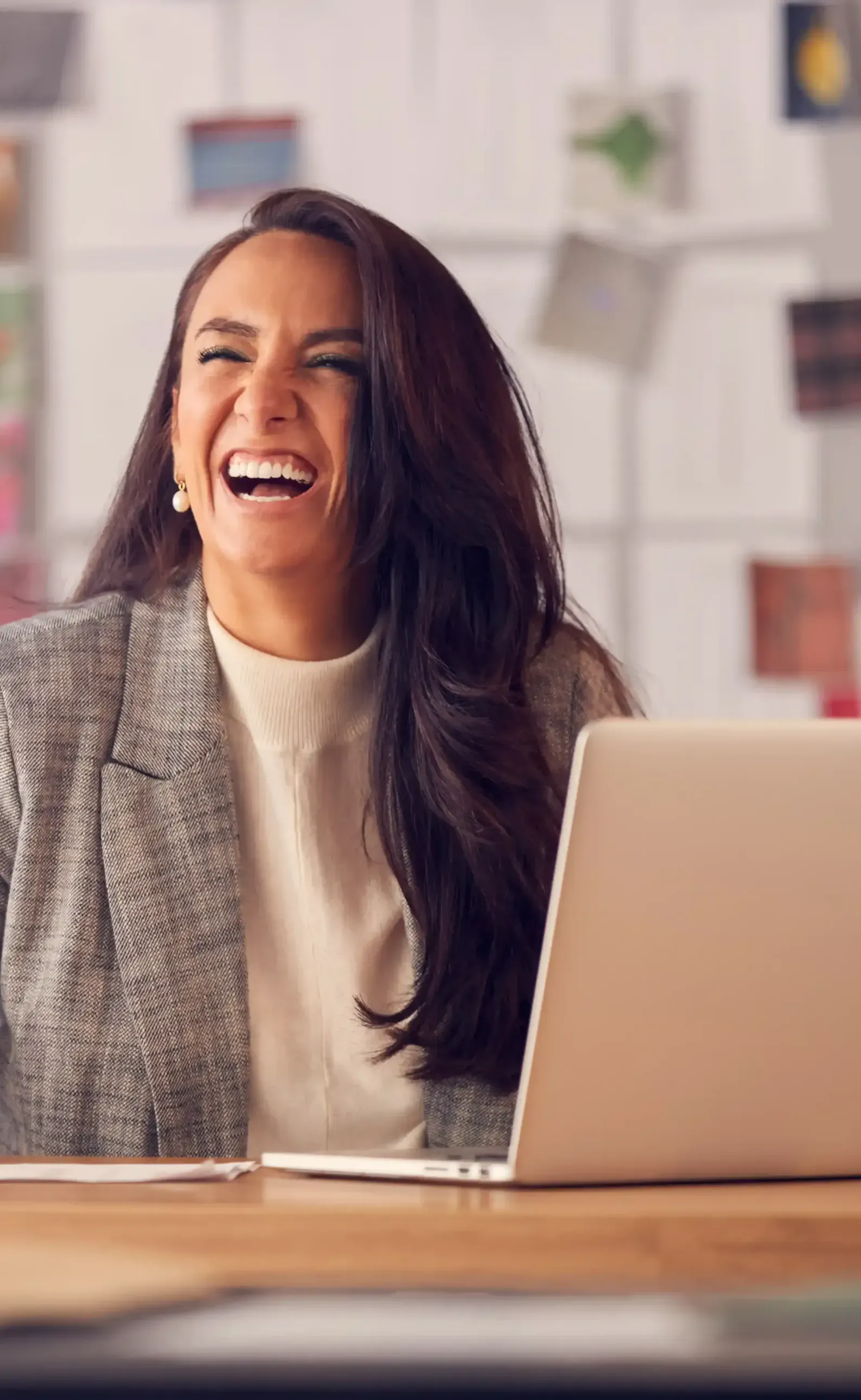 A woman is sitting at a desk laughing she learned personal branding from Broda Coaching.
