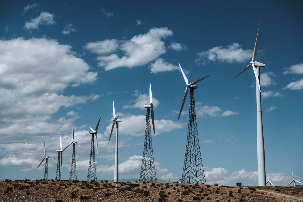 Wind turbines on a rocky plain under a blue sky with scattered clouds.