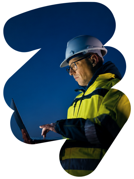 Worker in hard hat and yellow jacket using a laptop against a dark blue background