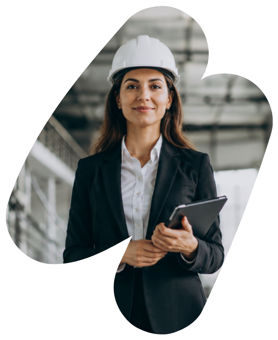 Woman in a hard hat and blazer holding a tablet in an industrial setting