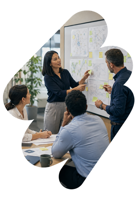 Team meeting with coworkers discussing ideas on a whiteboard in an office.