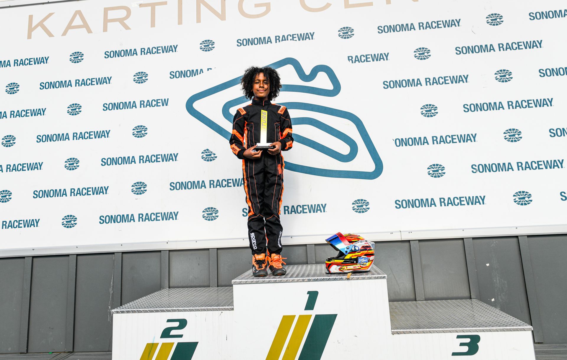 Kylo Washington on the P1 podium step holding his karting trophy