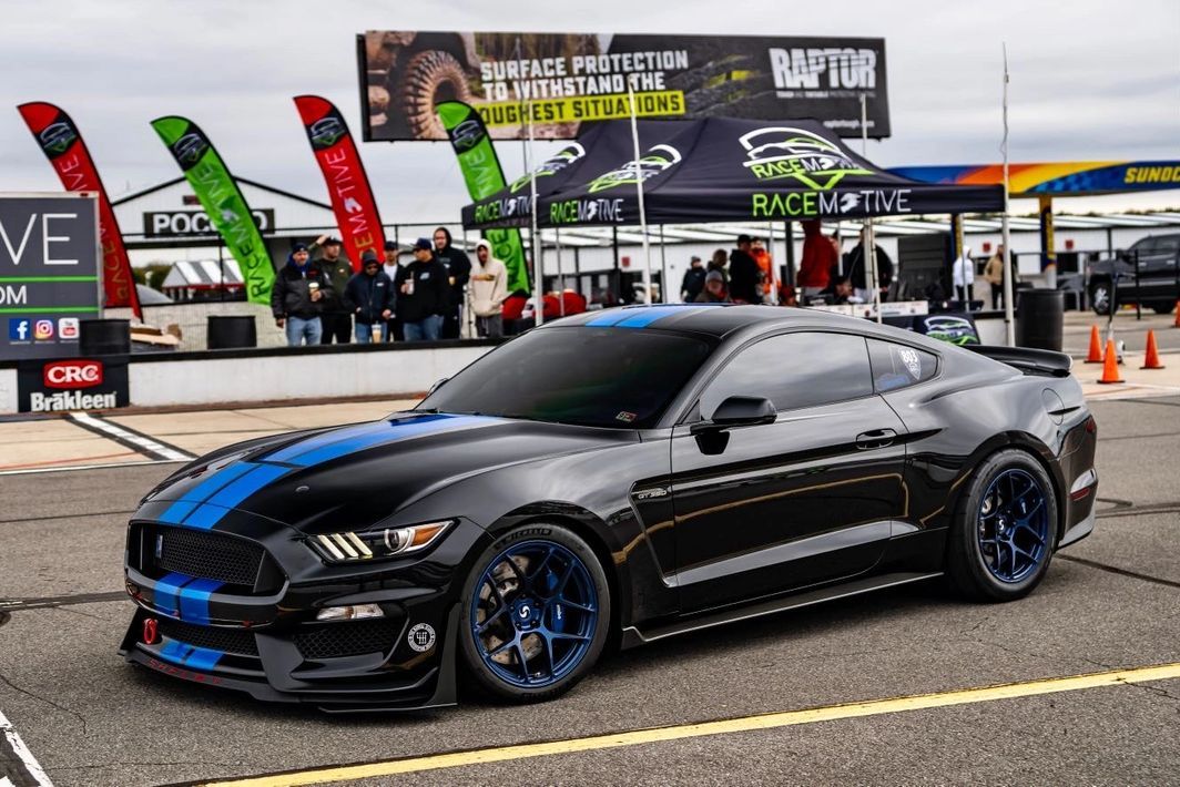 A black and blue mustang is parked in a parking lot.