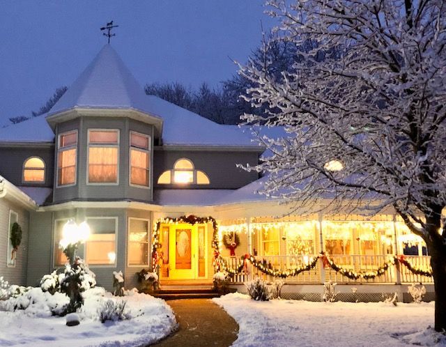 A house decorated for christmas with snow on the ground