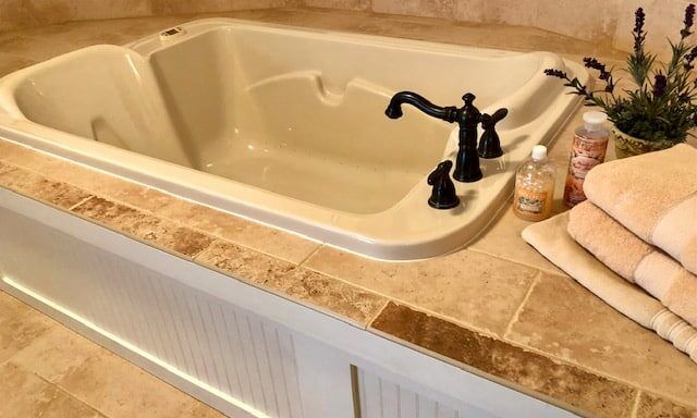 A bathtub in a bathroom next to a stack of towels