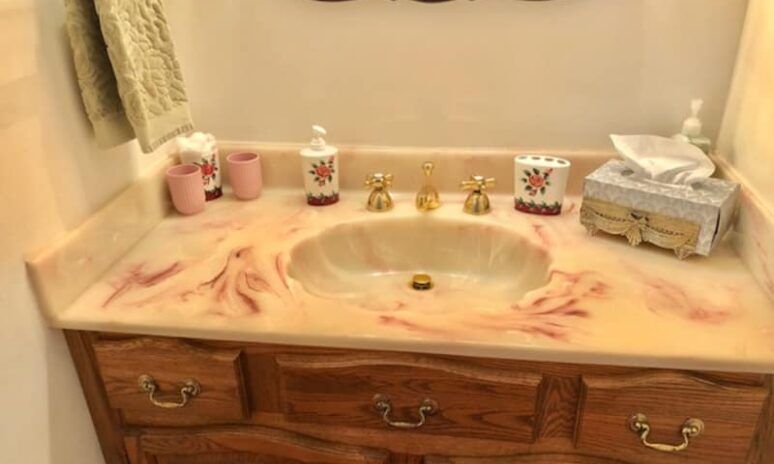 A bathroom sink with a marble counter top and a wooden cabinet.