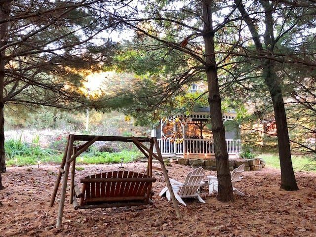 A wooden swing is sitting in the middle of a forest.
