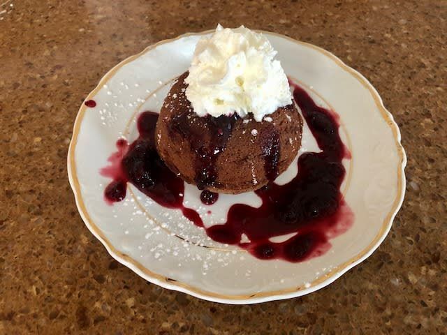 A white plate topped with a chocolate cake and whipped cream