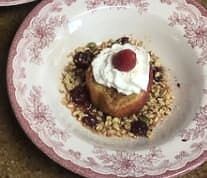Four plates of food with whipped cream and raspberries on them